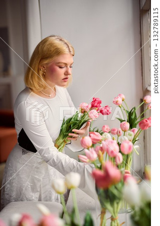 Reflective artist methodically prepares flowers in gentle 132789115