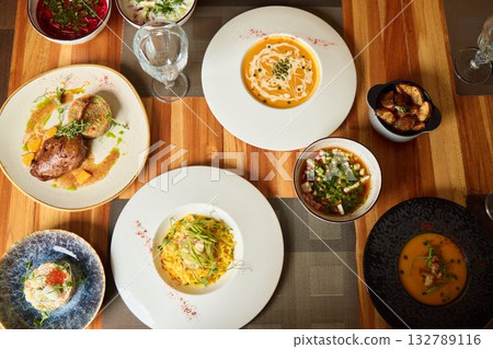 A Variety of Gourmet Dishes Artistically Spread Across a Rustic Wooden Table Setting 132789116
