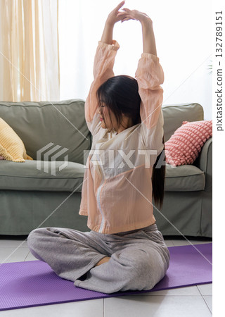 Healthy lifestyle health for woman teen, exercise yoga physica sport workout at home, stretching arms upwards on purple mat, promoting wellbeing and fitness. 132789151