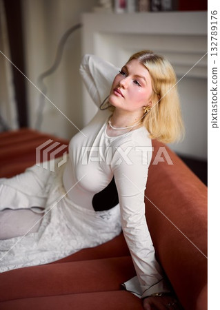Calm blonde woman seated comfortably near cozy fireplace Calm blonde woman seated comfortably near cozy fireplace 132789176