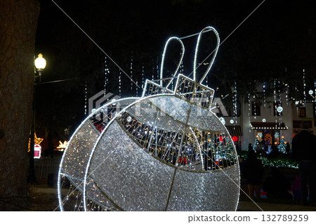 Bright white ornament with LED lights shines against a festive night scene. Holiday decoration shows detailed texture, sparkle, and glowing edges. Bright white ornament with LED lights shines against a festive night scene. Holiday decoration shows detailed texture, sparkle, and glowing edges. 132789259