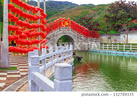 A traditional stone bridge with red lanterns in Nianshan Park, Sanya, Hainan, China. 132789335