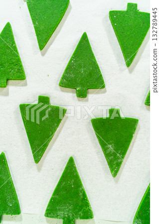 Multiple Green Gingerbread Cookies in Christmas tree shapes arranged in a pattern on a white background, forming a festive holiday display. Multiple Green Gingerbread Cookies in Christmas tree shapes arranged in a pattern on a white background, forming a festive holiday display. 132789445