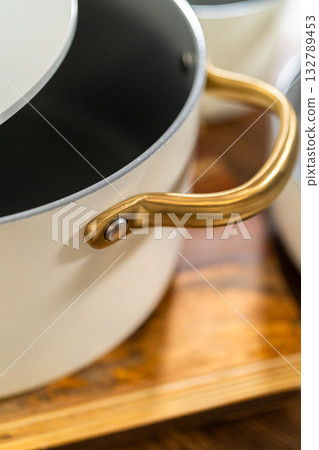 Top-down angle of a ceramic pot showing a curved gold side handle and soft light reflections on the matte surface. 132789453