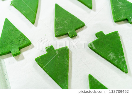 Multiple Green Gingerbread Cookies in Christmas tree shapes arranged in a pattern on a white background, forming a festive holiday display. Multiple Green Gingerbread Cookies in Christmas tree shapes arranged in a pattern on a white background, forming a festive holiday display. 132789462
