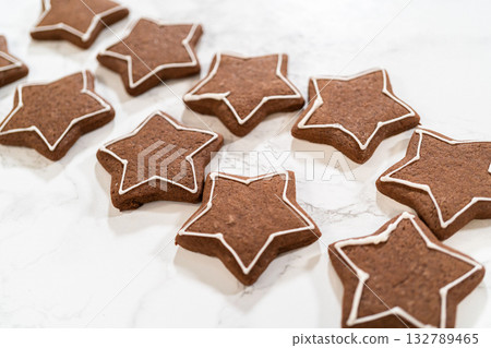 A group of freshly baked gingerbread star cookies spread out on a surface, ready for decorating or enjoying plain. A group of freshly baked gingerbread star cookies spread out on a surface, ready for decorating or enjoying plain. 132789465