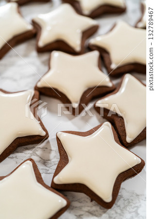 A neat arrangement of gingerbread star cookies covered in white royal icing, emphasizing their festive and uniform design. 132789467