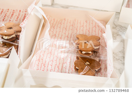 Captured from a close-up perspective, several open holiday cookie gift boxes display an assortment of decorated Christmas cookies, including gingerbread men, stars, and Christmas trees. The carefully Captured from a close-up perspective, several open holiday cookie gift boxes display an assortment of decorated Christmas cookies, including gingerbread men, stars, and Christmas trees. The carefully 132789468
