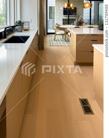 A kitchen walkway featuring wooden cabinetry, light flooring, and a built in floor vent. The interior design emphasizes functionality and bright atmosphere. A kitchen walkway featuring wooden cabinetry, light flooring, and a built in floor vent. The interior design emphasizes functionality and bright atmosphere. 132789488