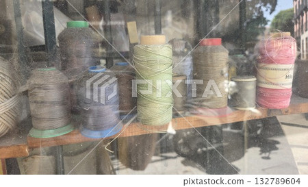 Vintage spool collection in rustic workshop setting for crafting and sewing projects. Fabric store window with skeins of thread Vintage spool collection in rustic workshop setting for crafting and sewing projects. Fabric store window with skeins of thread 132789604