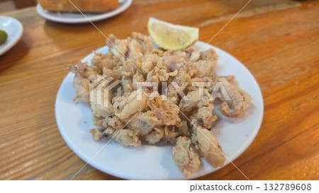 Crispy fried calamari with lemon on rustic wooden table setting. Traditional Spanish dish Crispy fried calamari with lemon on rustic wooden table setting. Traditional Spanish dish 132789608