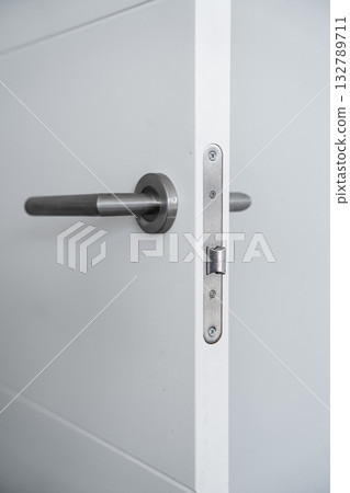 Close up of modern stainless steel door handle and lock mechanism on white door Close up of modern stainless steel door handle and lock mechanism on white door 132789711