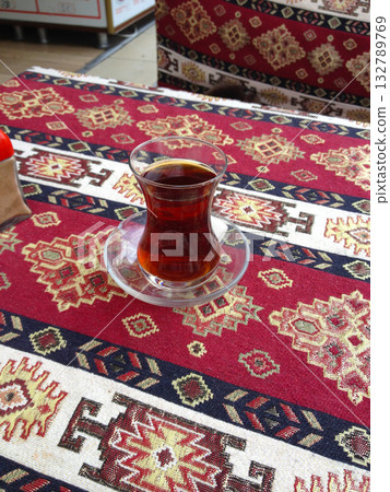 Turkish black tea served in a traditional glass on patterned fabric. Warmth, ritual, and cultural hospitality at a local cafe in Istanbul. 132789769