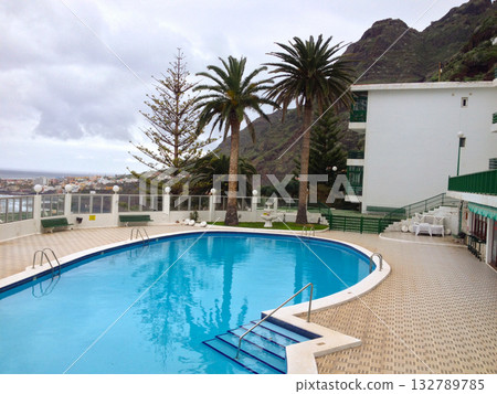 Hotel swimming pool with mountain view in Tenerife. Relaxation, leisure, and tropical island vacation surrounded by Atlantic beauty. 132789785