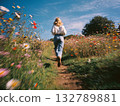 Woman running away in field, colorful summer flowers, bright sunny day photo. Blue jeans, white shirt, happy freedom concept. Beautiful woman running in field. 132789881