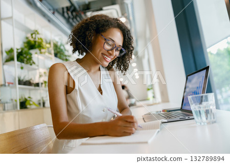 female notetaking session, woman diligently jotting down ideas and objectives in coffeehouse 132789894