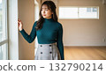 A woman in a turtleneck standing by the window in an empty room and looking outside 132790214