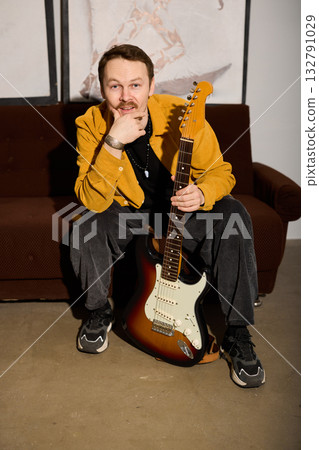 Informal photo showing man smiling with guitar in warm light 132791029