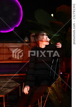 woman in black exhibits product with lively motions under purple lighting in showroom setting woman in black exhibits product with lively motions under purple lighting in showroom setting 132791341