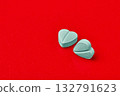 two blue heart pills on a red background. 132791623
