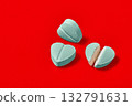 heart-shaped pill halves on a red background. 132791631