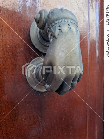 An elegant antique door handle design features a woman's hand grasping the knob. This distinctive piece adds charm and character to the vintage wooden door it adorns. 132791766
