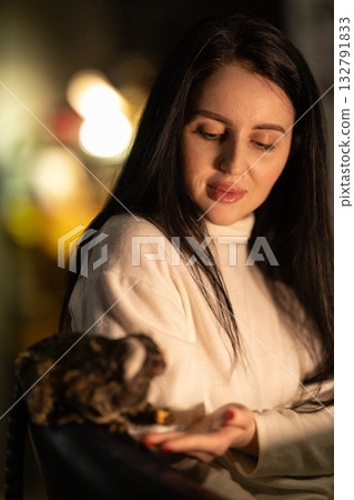 girl in a white sweater enjoys a gentle moment with a small marmoset on her palm inside a warm softly lit room in the evening. They share a playful connection. girl in a white sweater enjoys a gentle moment with a small marmoset on her palm inside a warm softly lit room in the evening. They share a playful connection. 132791833