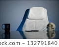 simple white chair sits in a softly lit workspace next to a black mug and a human skull. The scene conveys a minimalist aesthetic with an air of intrigue and contemplation. 132791840
