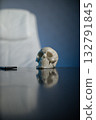 A skull is placed on a shiny table in a contemporary office. A white chair can be seen in the background suggesting a professional atmosphere. The lighting enhances the details. 132791845