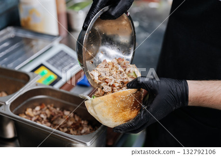 Chef preparing shawarma sandwich with grilled meat and fresh vegetables in pita bread Chef preparing shawarma sandwich with grilled meat and fresh vegetables in pita bread 132792106