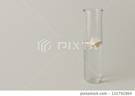 The paper boat floats in a tall glass flask. Space for text. The paper boat floats in a tall glass flask. Space for text. 132792864