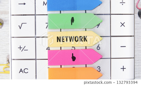 A white calculator displays numbers and mathematical symbols while arrow-shaped sticky notes, each in a different bright color, lay over the keys. One note says NETWORK in block letters 132793394
