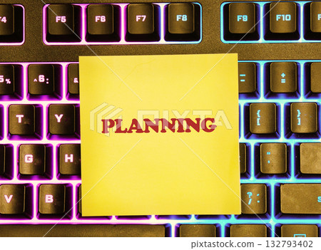 A yellow sticky note with the word PLANNING in red letters rests on a modern keyboard with colorful, backlit keys. It suggests preparation for future endeavors A yellow sticky note with the word PLANNING in red letters rests on a modern keyboard with colorful, backlit keys. It suggests preparation for future endeavors 132793402