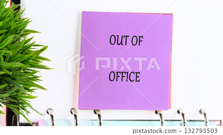 A lavender note boldly states OUT OF OFFICE, fastened to a ringed notebook next to a bright green plant, announcing a well deserved break from the daily grind A lavender note boldly states OUT OF OFFICE, fastened to a ringed notebook next to a bright green plant, announcing a well deserved break from the daily grind 132793503