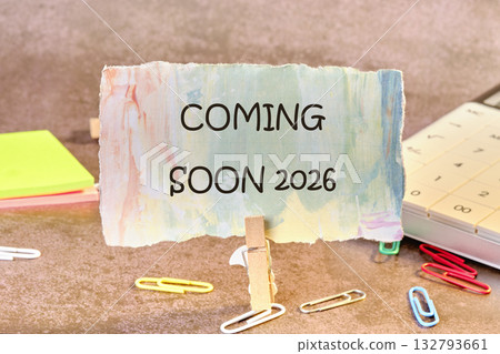 A decorative sign announces something is coming soon in 2026. A calendar and colorful paper clips suggest planning and anticipation for the upcoming event A decorative sign announces something is coming soon in 2026. A calendar and colorful paper clips suggest planning and anticipation for the upcoming event 132793661