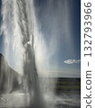 This is a view of the waterfall from behind the basin of Seljalandsfoss, a waterfall in southern Iceland, with the sunset visible beyond the waterfall. 132793966
