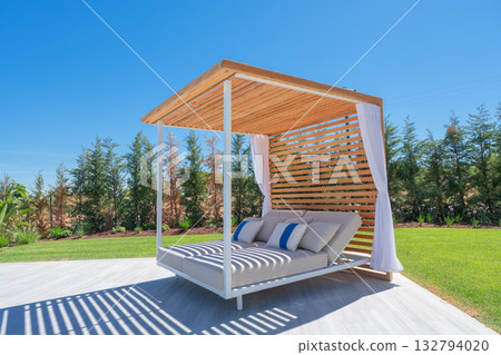 Stylish outdoor shelter, Charming striped lounging area, Elegant wooden pavilion with relaxing seating, Beautiful outdoor cabana featuring cushions and flowing drapes Stylish outdoor shelter, Charming striped lounging area, Elegant wooden pavilion with relaxing seating, Beautiful outdoor cabana featuring cushions and flowing drapes 132794020