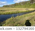 A clear stream, grassland, cliff mountains and small waterfall beyond Seljalandsfoss, a waterfall in southern Iceland. 132794160
