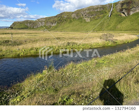冰島南部塞里雅蘭瀑布 (Seljalandsfoss) 遠處是一條清澈的小溪、一片草地、陡峭的山峰和一個小瀑布。 冰島南部塞里雅蘭瀑布 (Seljalandsfoss) 遠處是一條清澈的小溪、一片草地、陡峭的山峰和一個小瀑布。 132794160