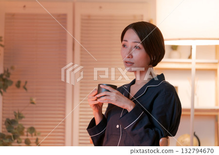 晚上，一位穿著睡衣的女子在房間裡喝著熱飲。 132794670