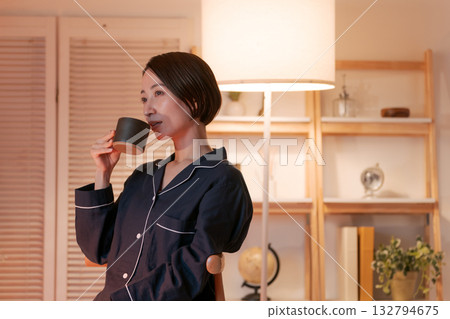 晚上，一位穿著睡衣的女子在房間裡喝著熱飲。 132794675