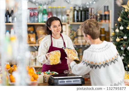 Female salesperson offers to buy chips to teenage boy in Christmas interior of grocery supermarket Female salesperson offers to buy chips to teenage boy in Christmas interior of grocery supermarket 132795877