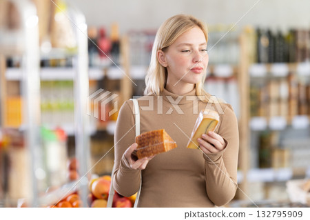 Girl buyers examine good, doubt and choose cheese in store Girl buyers examine good, doubt and choose cheese in store 132795909