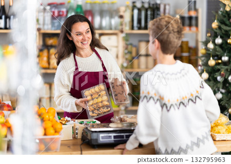Female employee sells cookies to teen boy on Christmas Eve. Female employee sells cookies to teen boy on Christmas Eve. 132795963