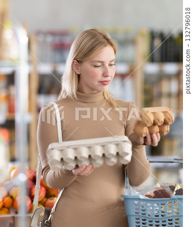 Girl buyer examine good, doubt and choose eggs in store 132796018
