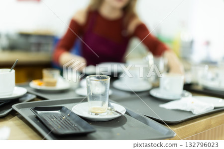 Young female waitress collects dirty dishes Young female waitress collects dirty dishes 132796023