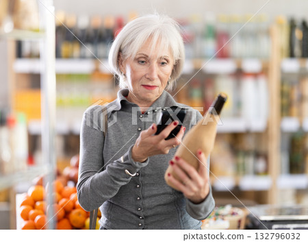 Checking expiration date of wine - elderly female shopper scans QR code on label of wine using smartphone 132796032