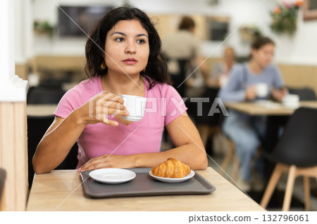 Attractive female sitting alone at table in cozy cafe, drinking fragrant coffee 132796061