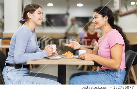 Two young girls talking over coffee and croissant in cafeteria 132796077