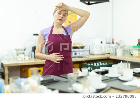 Tired female waitress collects dirty dishes Tired female waitress collects dirty dishes 132796093